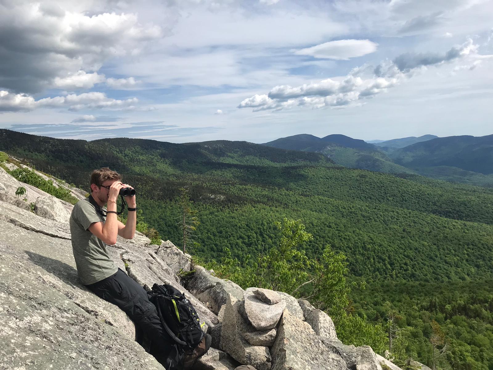 Man perched on a rocky mountain outcrop.