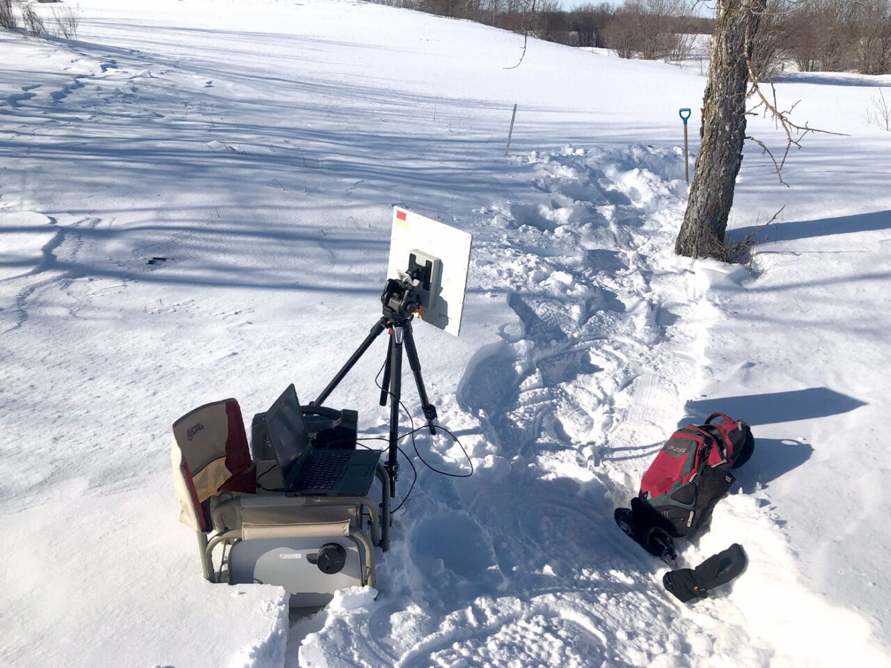 Study equipment outside: chair with computer on top, backpack and gloves in the snow.