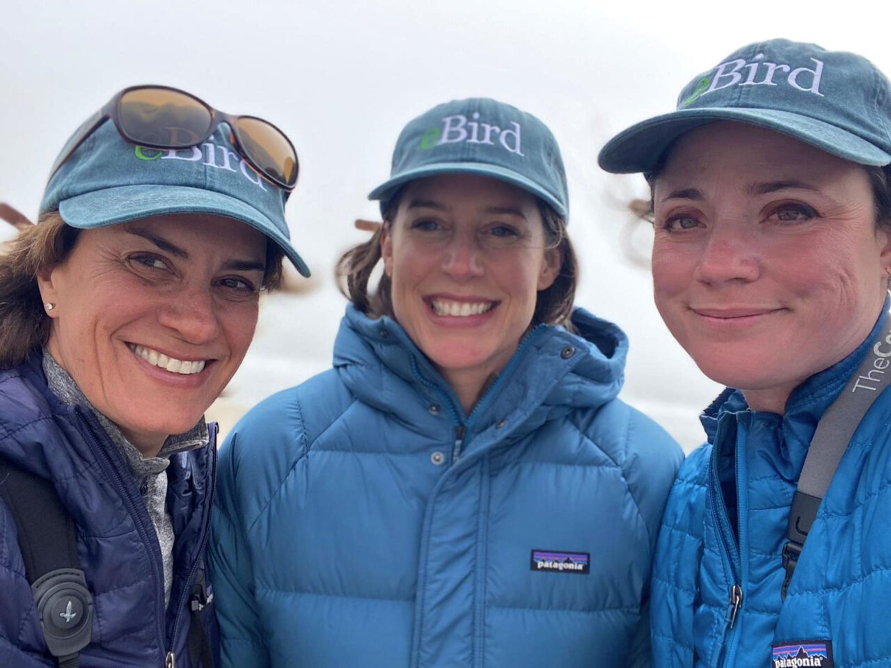 Three women smile at the camera.