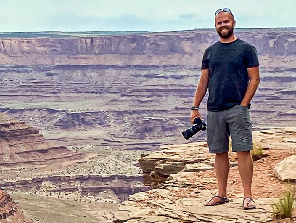 Man stands on a cliff in a red-rock canyon.